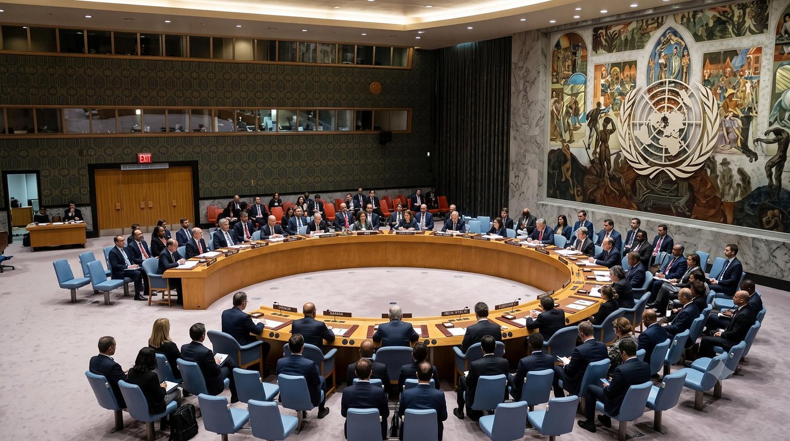A wide shot of the United Nations Security Council chamber in New York during a formal session, with delegates seated at the circular table.